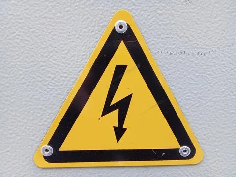 Close-up of yellow triangular sign warning of high voltage electrical hazard Stock Photos