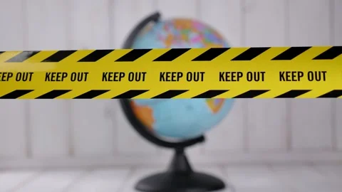 Close-up of a yellow warning tape KEEP OUT against the backdrop of a globe. Stock Footage 328024325