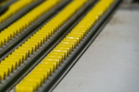 Close-up of yellowish, textured rectangular warehouse rollers with rounded .. Stock Photos