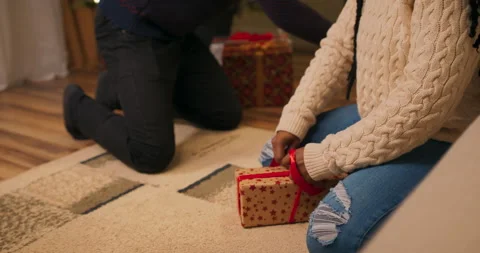 Close-up of young African-looking couple tying presents with red ribbon. Lovers 库存影片 211647252