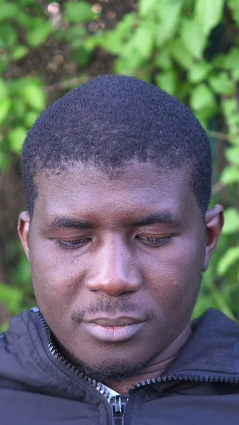 Close up of young African man sitting on park bench to relax outdoors 動画素材 335696268