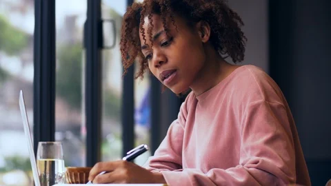 Close up of young African woman busy writing study indoor Stock Footage