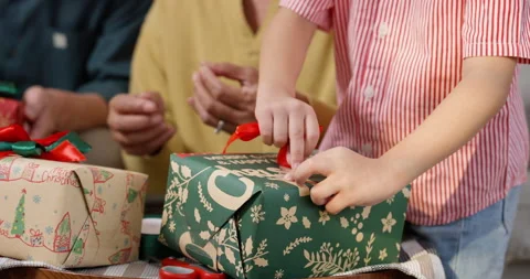 Close-up of young Asian boy wrapping Christmas gift with green and red pape.. Stock Footage 288749069