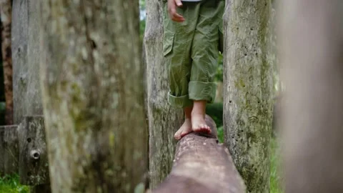 Close-up of a young Asian child walking barefoot and carefully balancing on.. Stock Footage 346600674