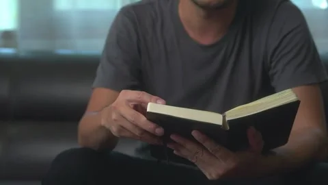 Close-up young asian man reading a book or novel while relaxing on a sofa i.. Stock Footage 246853584