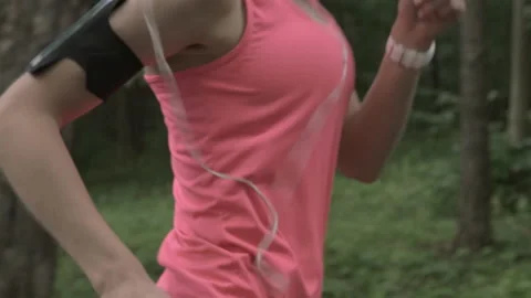 Close-up of young athletic runner listening to music while training in park. Stock Footage 132630414