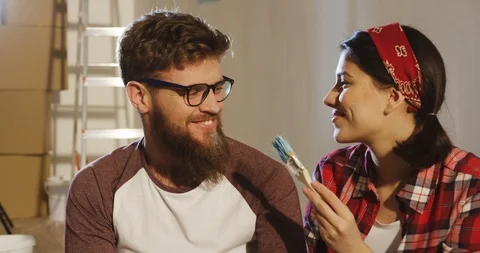 Close up of the young attractive funny man and woman painting on each other's Stock Footage 87587246