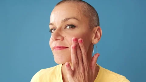 Close-up of young bald woman looking at the camera as if in mirror, standing on Stock Footage 297616865