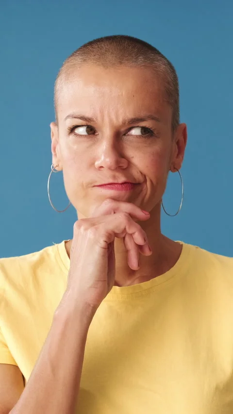 Close up, young bald woman making a choice standing on a blue background in the Stock Footage 297616663