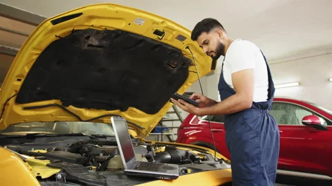 Close up of young bearded engineer mechanic under car hood checking engine with 스톡 동영상 234020968