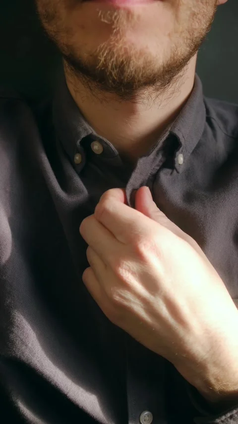Close up of a young bearded man buttoning up his shirt Stock Footage 337551077