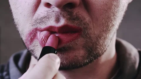 Close up of a young bearded man puts red lipstick on his lips. Lgbt concept Stock Footage 165069319