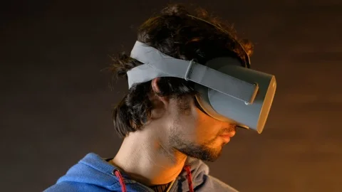 Close-up of young bearded man turning his head around in vr glasses Видео 101405643
