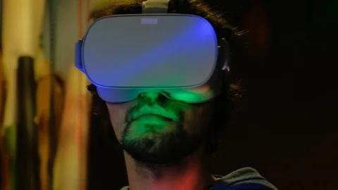 Close-up of young bearded man turning his head around in vr glasses Видео 101431669