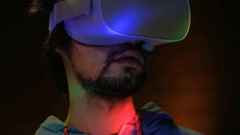 Close-up of young bearded man turning his head around in vr glasses Видео 101432025