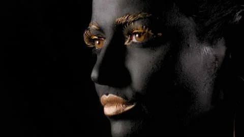 Close-up of a young beautiful woman's face with black and gold paint on her skin Stock Footage 144588771