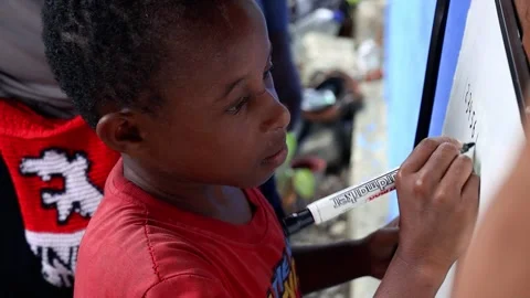 Close-up of a Young Black Child Learning to Write on a Whiteboard Outdoors 库存影片 318177631