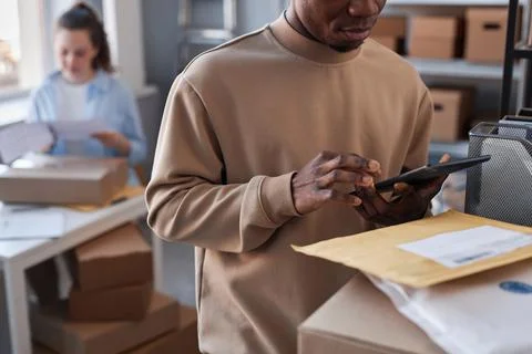 Close-up of young black man checking data in tablet in post office Stock Photos