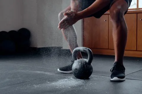 Close-up of young black man doing squats over kettlebell at the gym Stock Photos