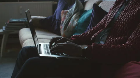 Close Up of Young Black Man Sitting on Sofa and Typing on Laptop Stock Footage 59864202