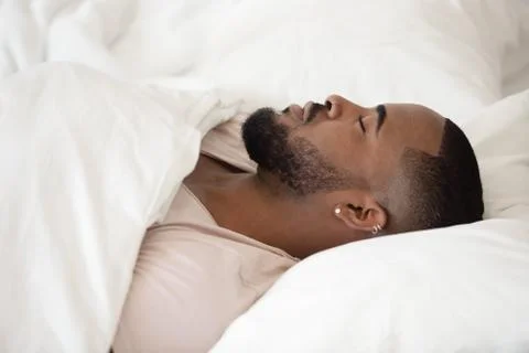 Close up young black man sleeping in bed. Stock Photos