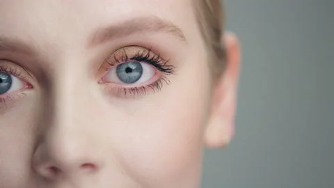 Close on young blonde model's face as she opens eyes to camera in split frame Stockbeeldmateriaal 193966896