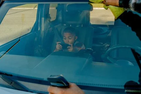 Close up of young boy excited while playing video game in passenger seat and dad Stock Photos