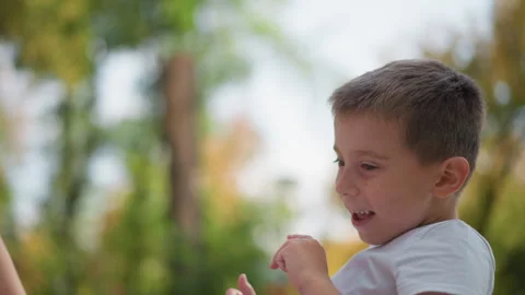 Close up of young boy extending arms to receive leaf from adult hands in outdoor Stock Footage 346723200