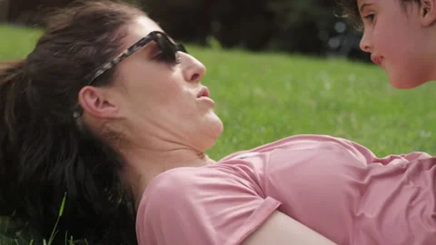 Close-up of a young boy laying on his mother's chest on the grass at the park Video stock 143623084