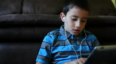 Close up of young boy learning on tablet wearing headphones Stock Footage 12296837