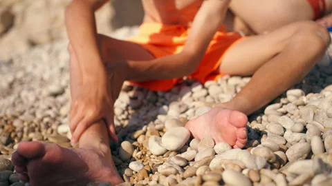 Close-up of young boy massaging painful ankle and leg while sitting on sunn.. Stock Footage 336267789
