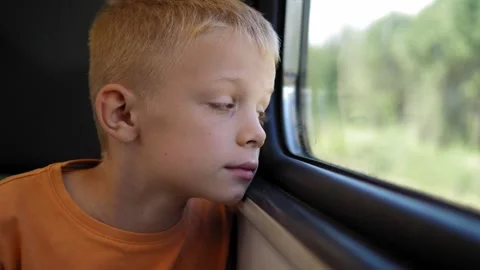 A close-up of a young boy riding on a train and looking out the window. Stock Footage 311151880
