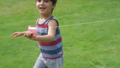 Close-up of a young boy running with a kite string in a park Stock-Footage 143622061