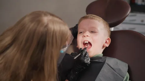 Close up of young boy undergoing oral examination with woman in clinical setting Stock Footage 345088382