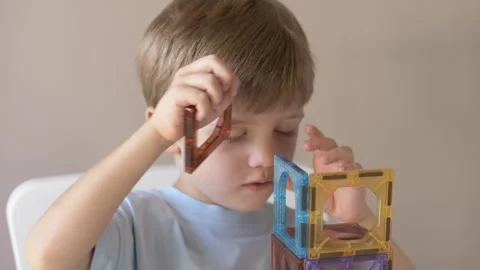 Close-up of a young boys face as he intently watches and places pieces on a Stock Footage 318294640
