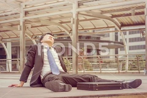 Close up of young business man sitting failed and stressed outside office Stock Photos