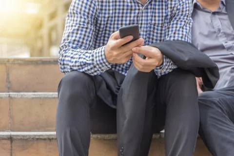Close up of young business man using mobile smartphone sitting on stairs Фото