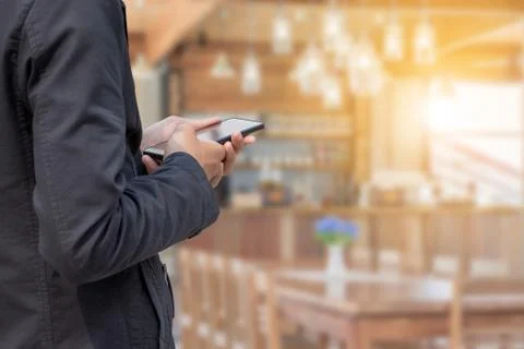 Close up of young business man using mobile smartphone blurry coffee shop 写真素材