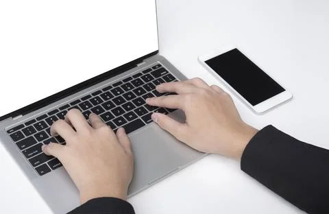 Close up young businessman hand using laptop with smartphone on white table.. Stock Photos