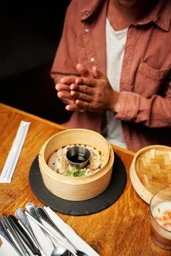Close-up of young caucasian man in casual clothing with dumplings in steamer at Stock Photos