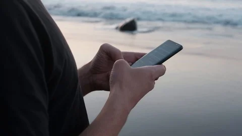 Close up of young caucasian man scrolling and using his smartphone at sunset on Stock Footage 123687161