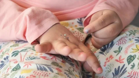 Close up of a young child playing with glitter on their hand, a captivating.. Stockbeeldmateriaal 333155933