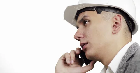 Close-up of a young construction worker in a white helmet talking on a mobile ph Stock Footage 86364596