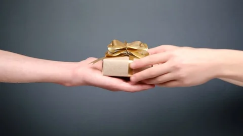 Close up of young couple hands holding gift box on grey background. Stock Footage 120739345