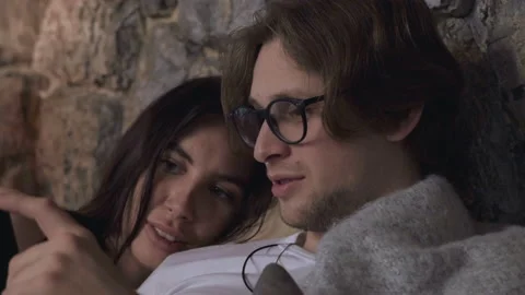 Close Up Of A Young Couple Lying In Bed Chatting Looking At Photos Stock Footage 137731853