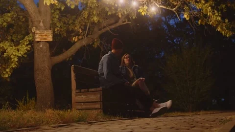 Close up of young couple sits on bench in night park Stock Footage 143645875