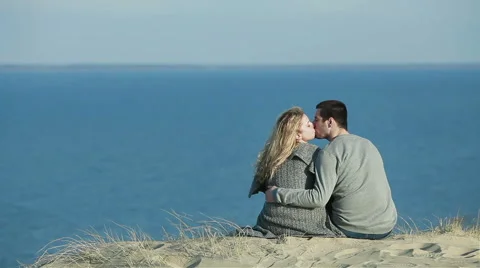Close up of young couple sitting embracing on the top of a dune hill and talking Stock Footage 49986759