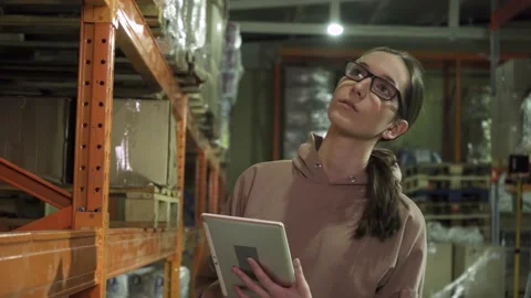 Close-up of a young employee with a computer tablet, working in the warehouse Stock Footage 190998144