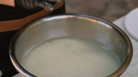 Close-up of young female chef gloved hand over metal bowl with rice soaked for Stock Footage 333030850