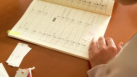 Close-up of a young foreign woman's hand as she is writing kanji  to learn Japan Stock Footage 296654980